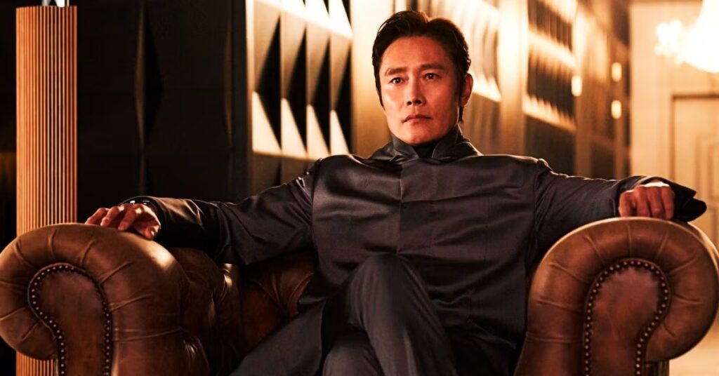 Antagonist of Round 6 wearing an all-black outfit and sitting on a leather couch